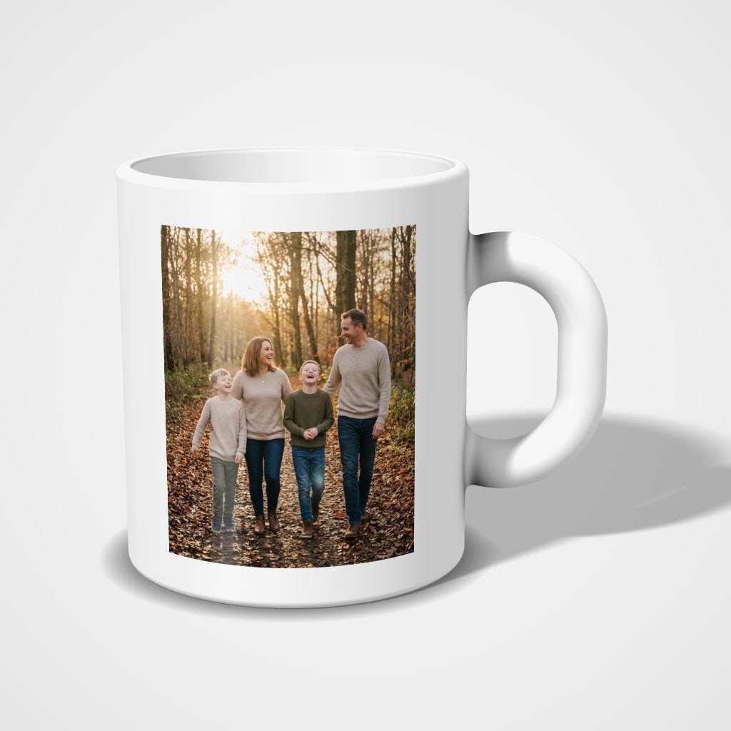 A white mug with a photo of a family walking through autumn woods printed on the side facing the camera, handle to the right