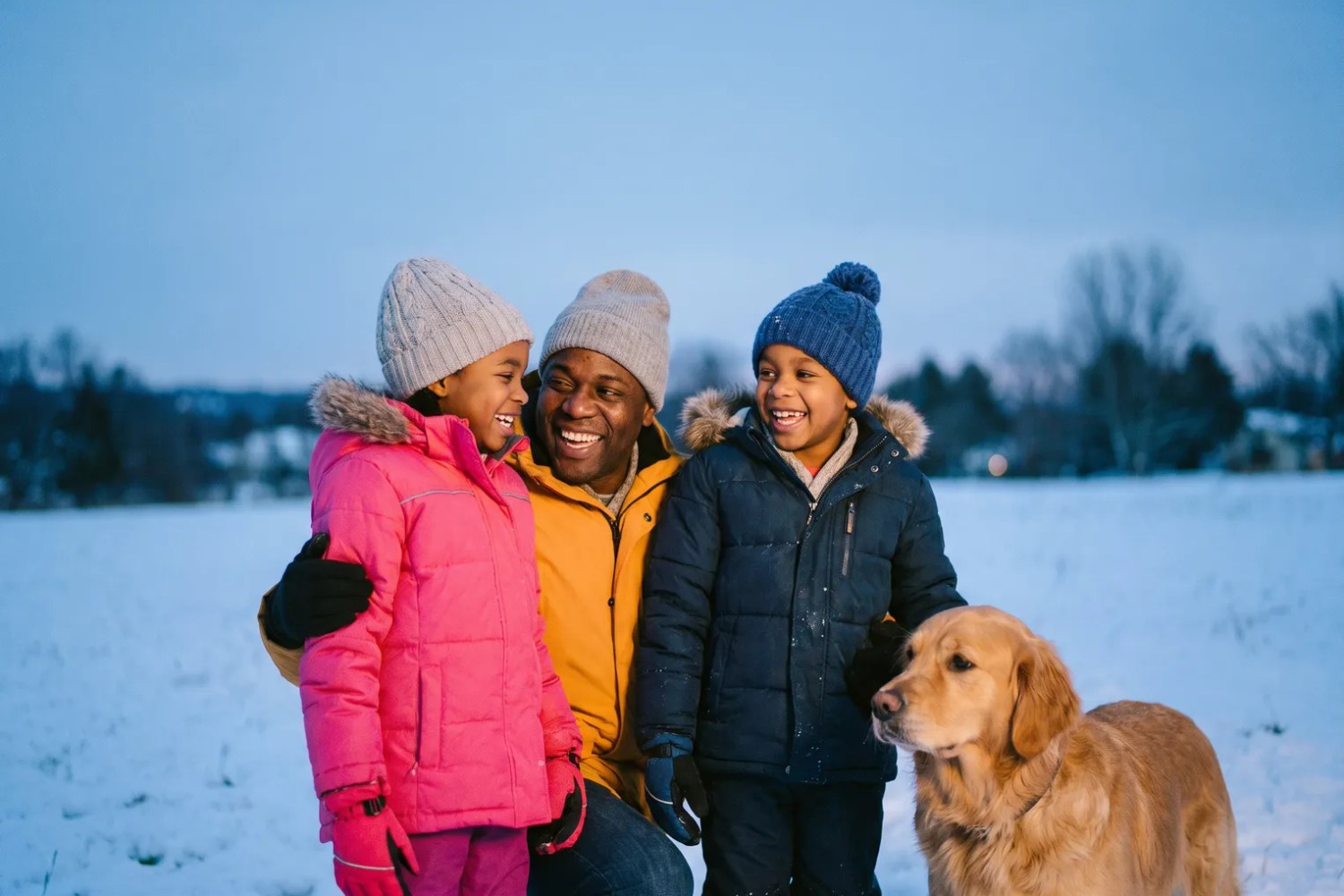 A snapshot of a father and two children with a golden retriever in a snowy field